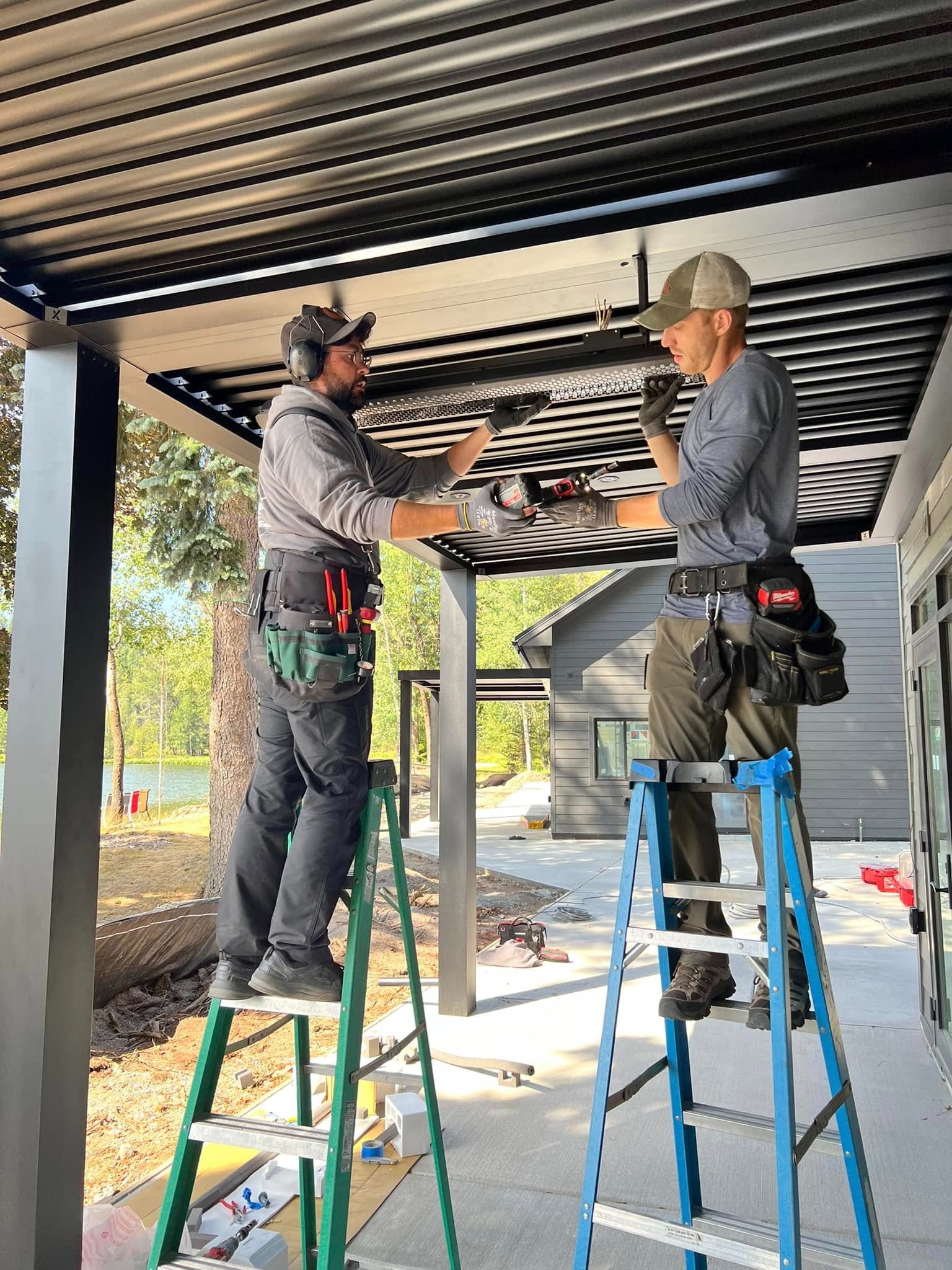 Crescent Electric crew installing electrical equipment beneath a modern covered patio